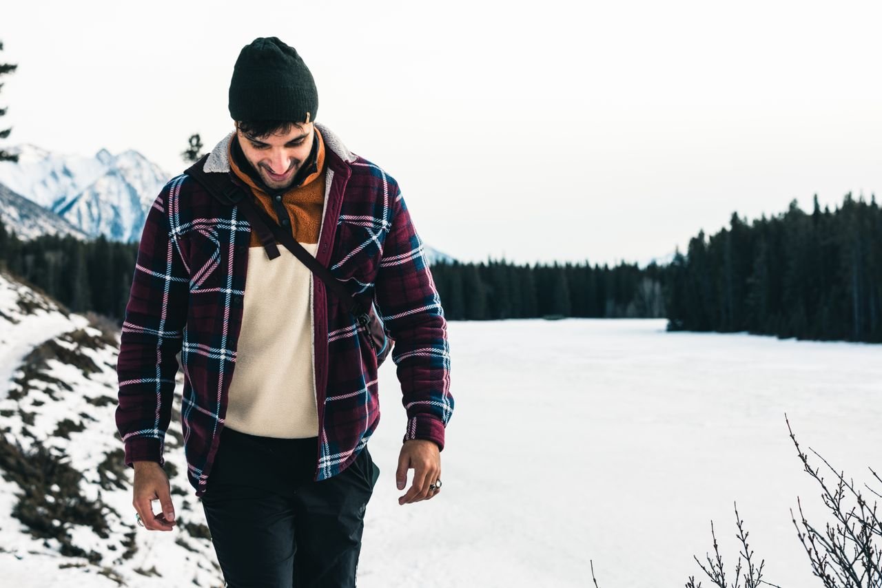 collection-05 A man enjoys winter hiking in Banff, Canada, surrounded by snowy mountains and a frozen lake.